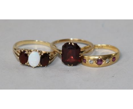 A 9ct gold, opal and garnet ring, scrolled carved mount, an 18ct gold, ruby and diamond gypsy-set ring and another 9ct gold r