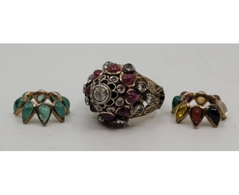 An Indian yellow metal, and multi-gem set ring, the raised mount having three different coloured gem set bezels, size UK K.&n
