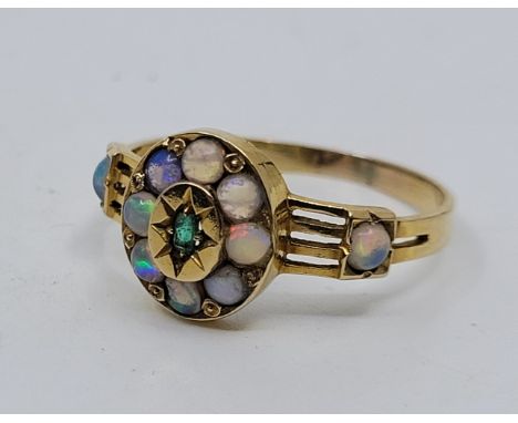 An 18ct gold, emerald and opal ring, the oval mount with raised centre illusion set single baguette cut emerald bordered by e