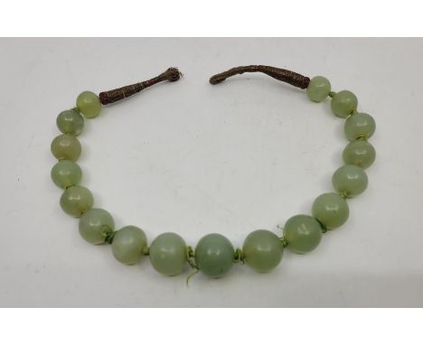 A string of green nephrite jade beads, the largest to centre diameter 21mm x length 19mm, strung as a choker necklace, length