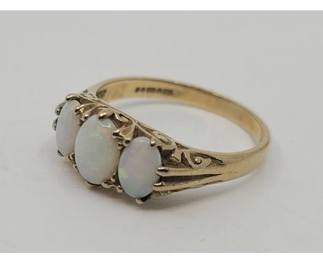 A 9ct. gold three stone opal ring, set three graduated oval cabochon opals above scrolled gallery, size UK N. (gross weight 2