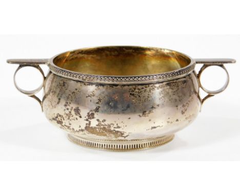 A George V silver circular sugar basin, with two ring handles and guilloche border, raised on a circular pierced foot, Sheffi