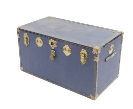 A 20thC travel trunk, in blue material with studded black outline and leather handles with metal mounts and locks, 89cm H, 83