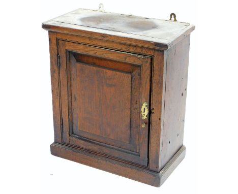 A 17thC oak wall cupboard, the top with a moulded edge above a panel door enclosing a plain shelf and a shaped shelf on a pli