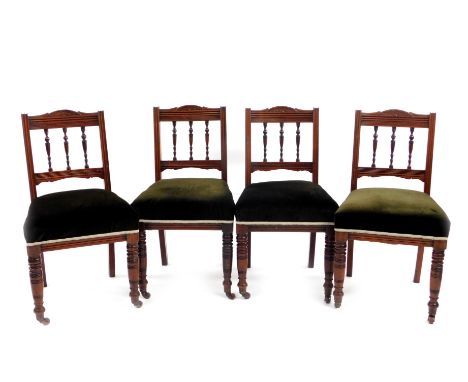 A set of four Edwardian walnut dining chairs, with comb cresting rails, turned splats and overstuffed seats on turned front l