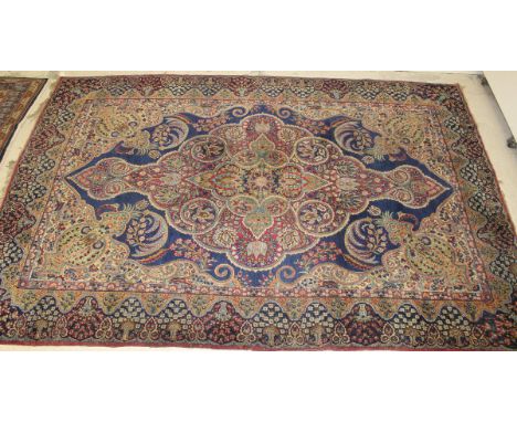 A Persian carpet, the central floral medallion on a blue and cream ground with all-over floral decoration, within a pink, mus