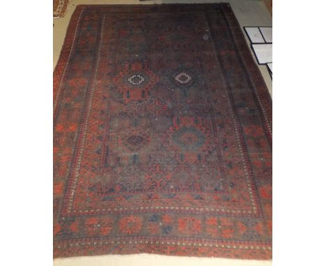 A Beluch village tribal carpet, the centrefield with stylised floral motifs in red, dark blue and cream on a madder ground wi