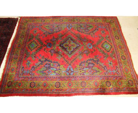 A Caucasian carpet, the central diamond shaped medallion in green, turquoise, dark blue and yellow on a red motif decorated g