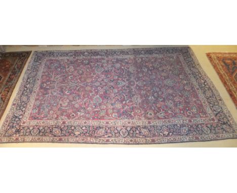 A Persian carpet, the all-over stylised floral and foilate decoration on a red ground within dark blue, red, cream and blue f