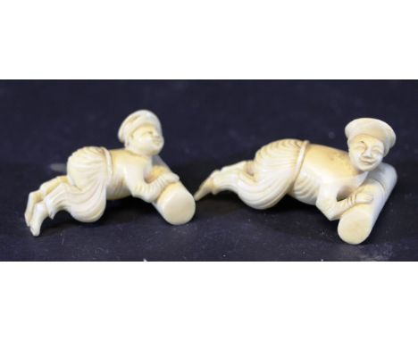 A pair of 19th Century Chinese carved ivory chopstick rests as figures pushing logs, 6.5 cm and 7.5 cm long