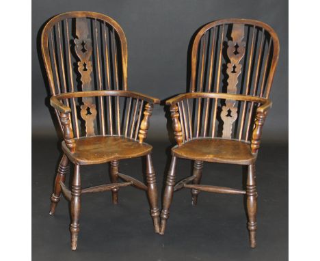 Two 19th Century Windsor type stick back armchairs in ash and elm, the fretwork carved back splats above a shaped seat on tur