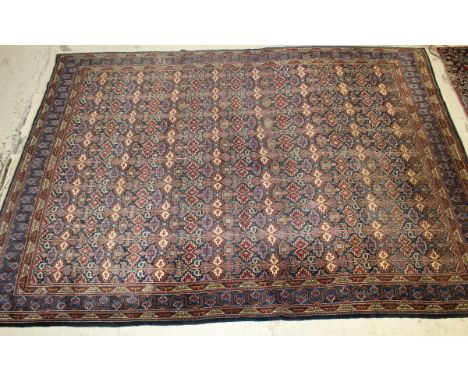 A Caucasian carpet, the centre ground with all-over repeating motifs in cinnamon, blue, green and cream on a dark blue / blac