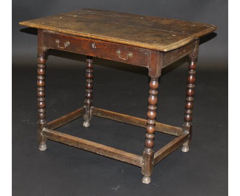 A circa 1700 oak side table, the two plank top with moulded edge above a single frieze drawer on bobbin turned supports unite