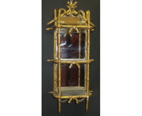 A 19th Century gilt and gesso framed three tier wall shelf with mirrored back, with swag and bow decorated finial, with bambo