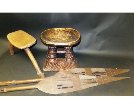 A Lobi wooden three legged stool, an African carved wooden stool, and two Nigerian ceremonial wooden paddles, tallest stool 2