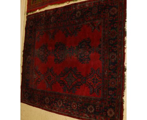 A Turkey carpet, the three central linked medallions in blue and green on a red ground, within dark blue, red, green and oran