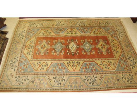 A Turkish carpet, the five central diamond shaped medallions in cream, pale blue, green and pale terracotta, on a pale terrac