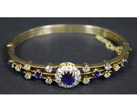 A gold mounted sapphire and diamond bangle, the centre sapphire approx 0.75 carats, within a band of twelve diamonds approx 0