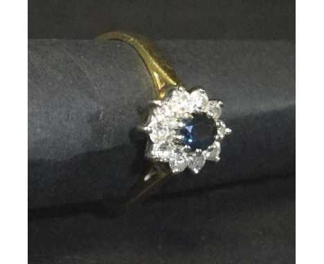 An 18 carat gold mounted sapphire and diamond cluster ring, the centre stone approx 0.2 carats, within a band of ten small di