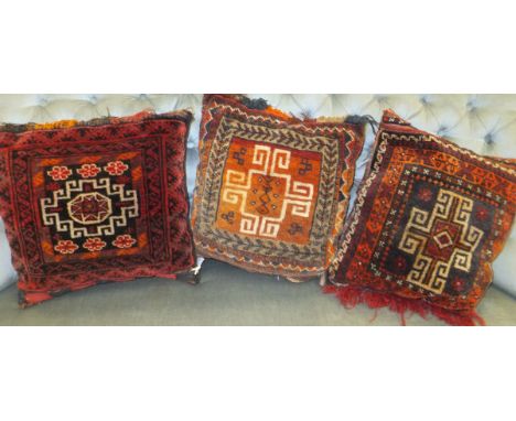 Three cushions with Caucasian carpet panels to fronts with red and black grounds  