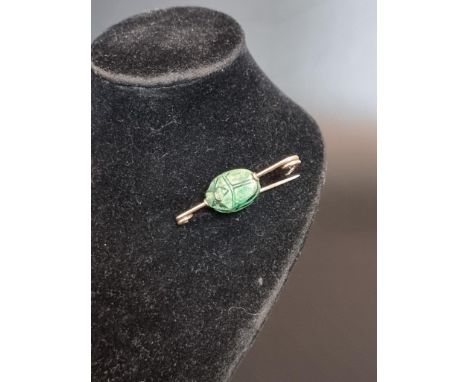 An early 20th century yellow metal bar brooch, set central revolving green ceramic scarab beetle, 4cm. 