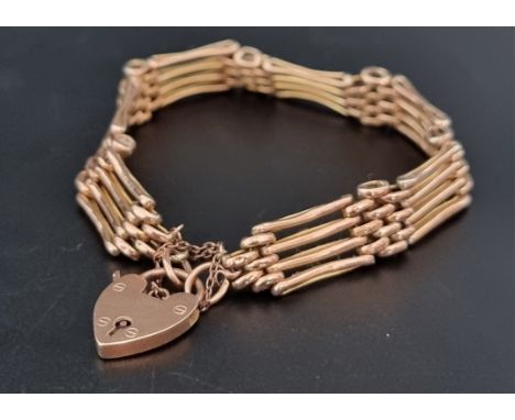 A yellow metal gate link bracelet, with a heart shaped padlock clasp. 