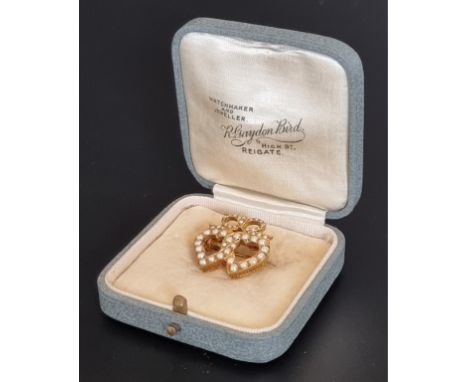 A Victorian yellow metal and seed pearl entwined heart brooch, 2cm wide. 