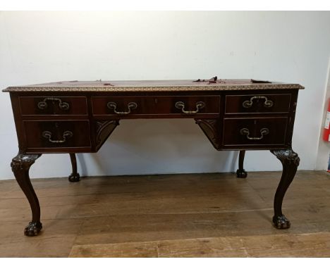 A mahogany kneehole desk, having five drawers, flanked by faux drawers, on carved cabriole legs, and claw and ball feet, 140 