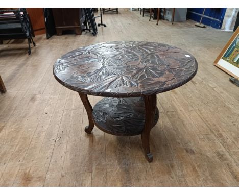 A Liberty style two tier table, carved lillies, 75 cm diameter