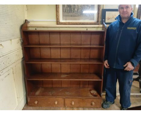 A stained pine waterfall bookcase, the base with two drawers, 124 cm wide