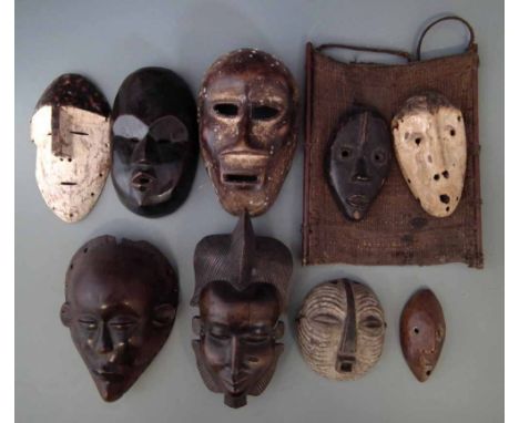 Nine African masks carved in various tribal styles, two attached to a textile backing, the largest measures 23cm high     All