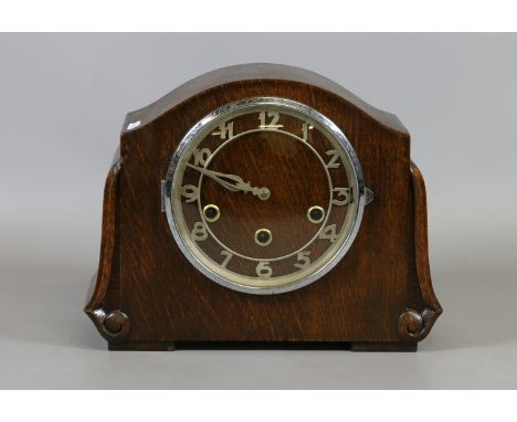 An early C20th oak cased mantel clock. The stylized Arabic numeral dial encloses three train eight day movement.