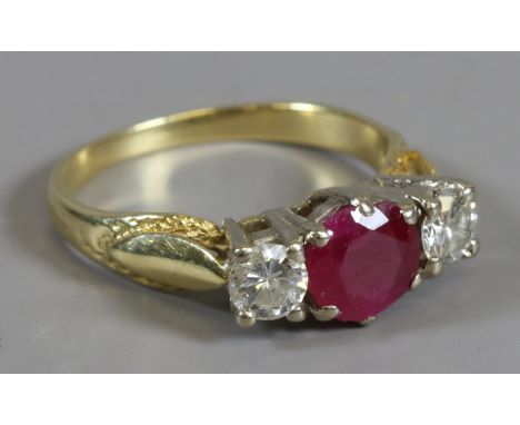 A gold ring set with a large round cut ruby approximately 0.7ct flanked by a pair of brilliant cut diamonds approximately 0.2