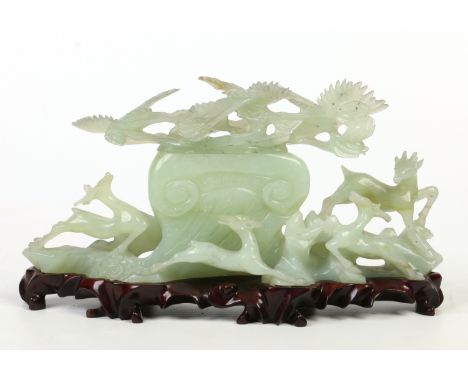 A Chinese celadon jade ornate box and cover of ruyi form raised on a carved hardwood plinth, of elongated form carved with cr