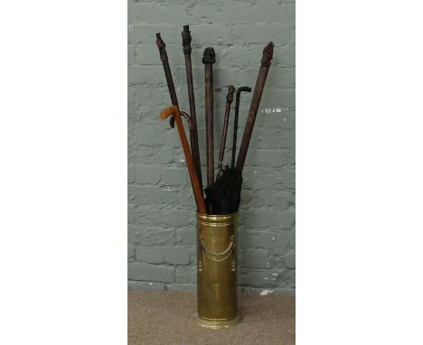 A hammered brass stick stand and collection of sticks and parasols some with figural terminals.