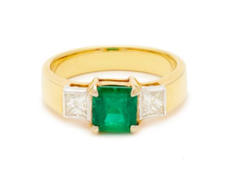 AN EMERALD AND DIAMOND RING An 18k yellow gold band with central step cut emerald, flanked with two square cut diamonds to ea