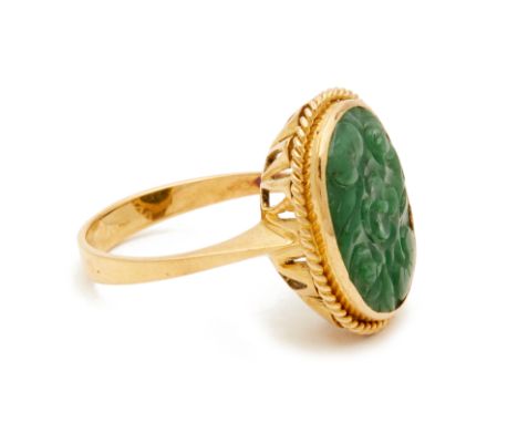 A CARVED JADE RING An 18k yellow gold band with a carved foliate design to the jade and rope twist border
 Hong Kong size 18 