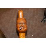 A carved walking stick, the head in the form of Wi