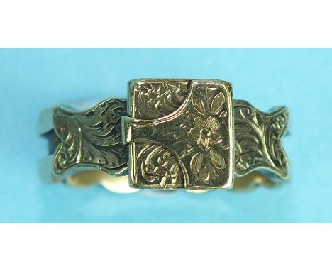 A Victorian yellow metal mourning ring, the floral engraved hinged front opening to reveal a hair locket, on scalloped shank,