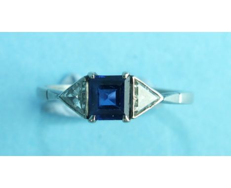 A sapphire three-stone diamond ring claw-set a square-cut sapphire between two triangular-cut diamonds, in platinum mount, si