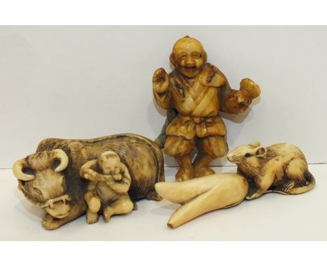 A 19th century Japanese ivory netsuke of a boy and a buffalo, (tail damaged), another of a rat eating a vegetable and one oth