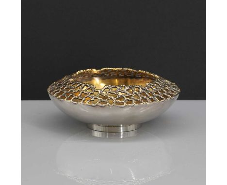 A silver-gilt bowl,by Stuart Devlin, London 1972,of flattened form with a pierced textured organic rim, on a low foot, 10.5cm