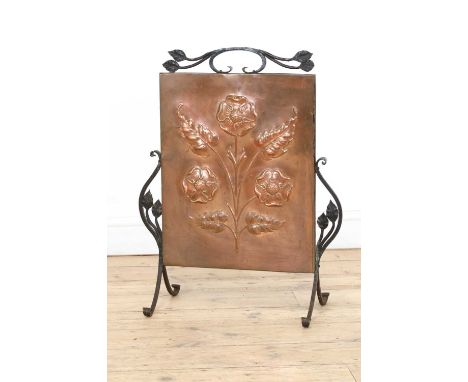 An Arts and Crafts copper embossed fire screen, centred with stylised flowers, mounted in a wrought iron frame, 55cm wide 70c