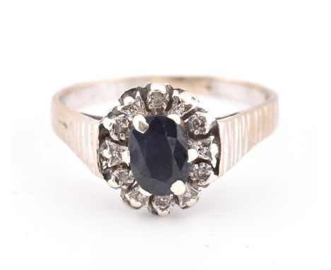 A hallmarked 9ct gold sapphire and diamond cluster ring. The 9ct yellow gold ring set with a central claw set oval cut sapphi
