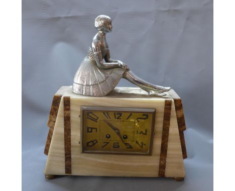 An Art Deco mantel clock with plated finial in the form of a seated young girl, having brass Arabic dial, drum movement, stri