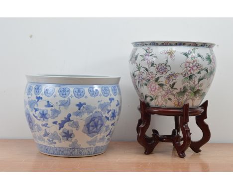 Two 20th century Chinese ceramic fish bowls, one with a blue and white design, the other a floral design on a hardwood stand 