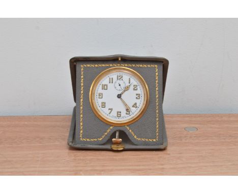 A 1930's travelling clock, in a foldable leatherette case, the dial with Arabic numerals, case dimensions  10.5cm x 10.5cm  