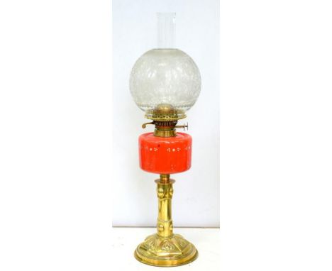 AN EDWARDIAN EMBOSSED BRASS OIL LAMP WITH ENAMELLED RED GLASS FOUNT AND BRASS BURNER, ETCHED SHADE, 57CM H EXCLUDING CHIMNEY