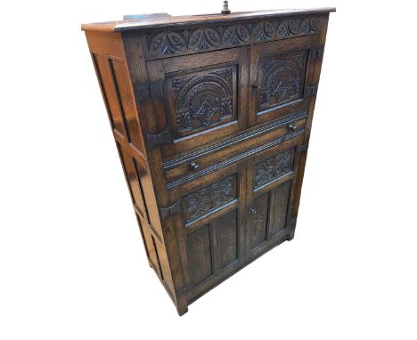 Carved oak cocktail cabinet having double cupboard doors above sliding shelf with larger double cupboard below, 43cm by 91cm 