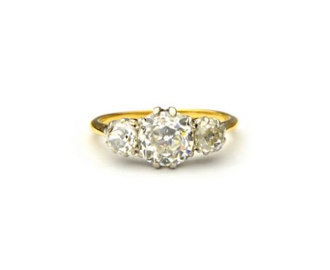 A gold and diamond set three stone ring, claw set with the principal cushion shaped diamond at the centre, between two smalle